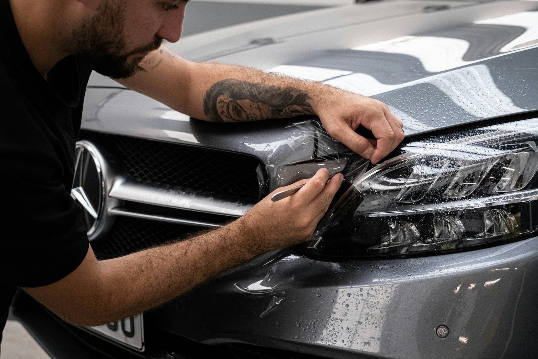A detailer waxing the hood of a car.